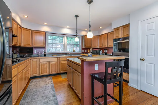 a kitchen with stainless steel appliances granite countertop wooden cabinets a center island and a refrigerator