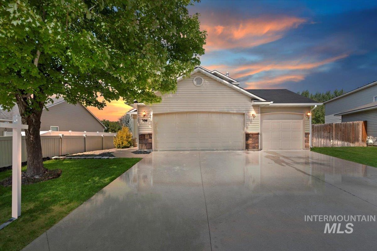 View of front of house with stone siding, concrete driveway, and an attached garage