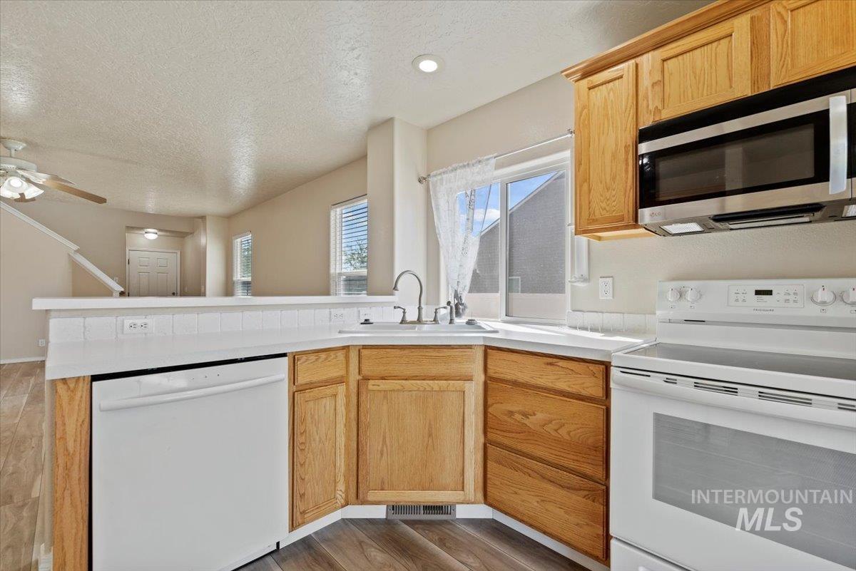 994 North Gray Cloud Way Meridian, ID 83642 - Photo 13 of 28 Kitchen with white appliances, a textured ceiling, light countertops, light wood-style floors, and a peninsula