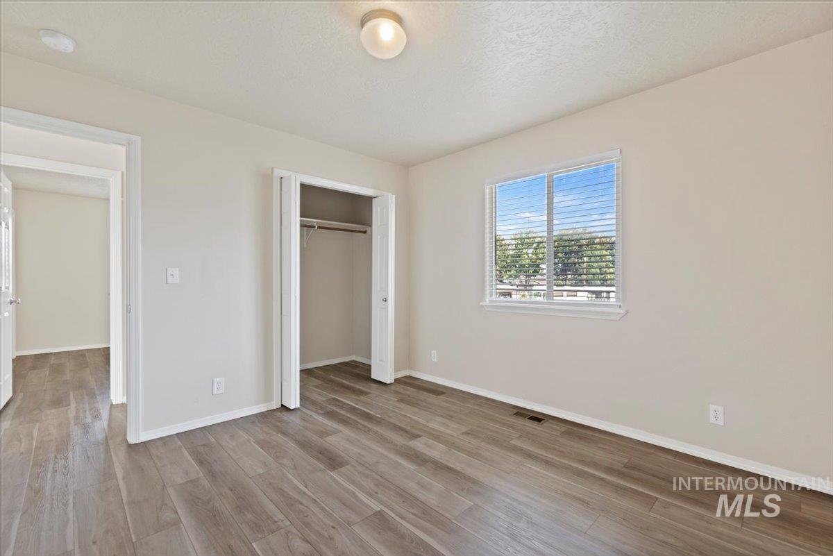 994 North Gray Cloud Way Meridian, ID 83642 - Photo 16 of 28 Unfurnished bedroom with light wood-style flooring, a closet, and a textured ceiling