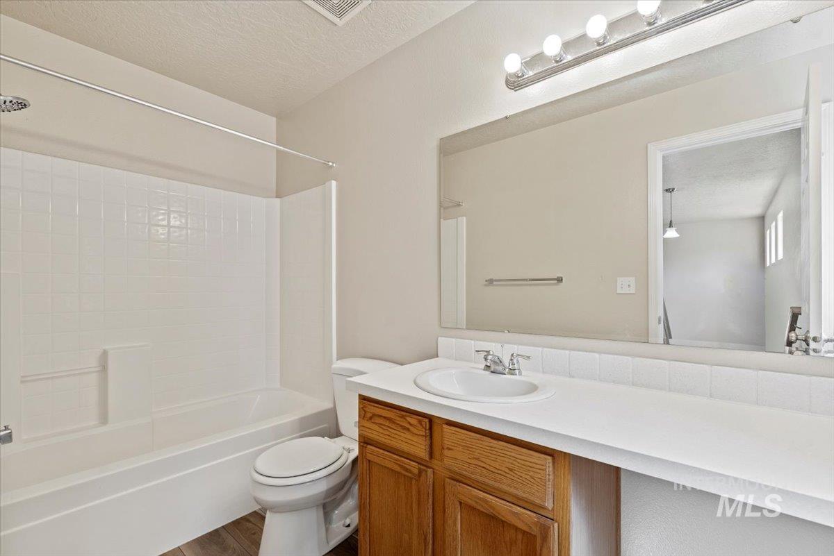 994 North Gray Cloud Way Meridian, ID 83642 - Photo 23 of 28 Bathroom with a textured ceiling, vanity, tub / shower combination, and dark wood finished floors