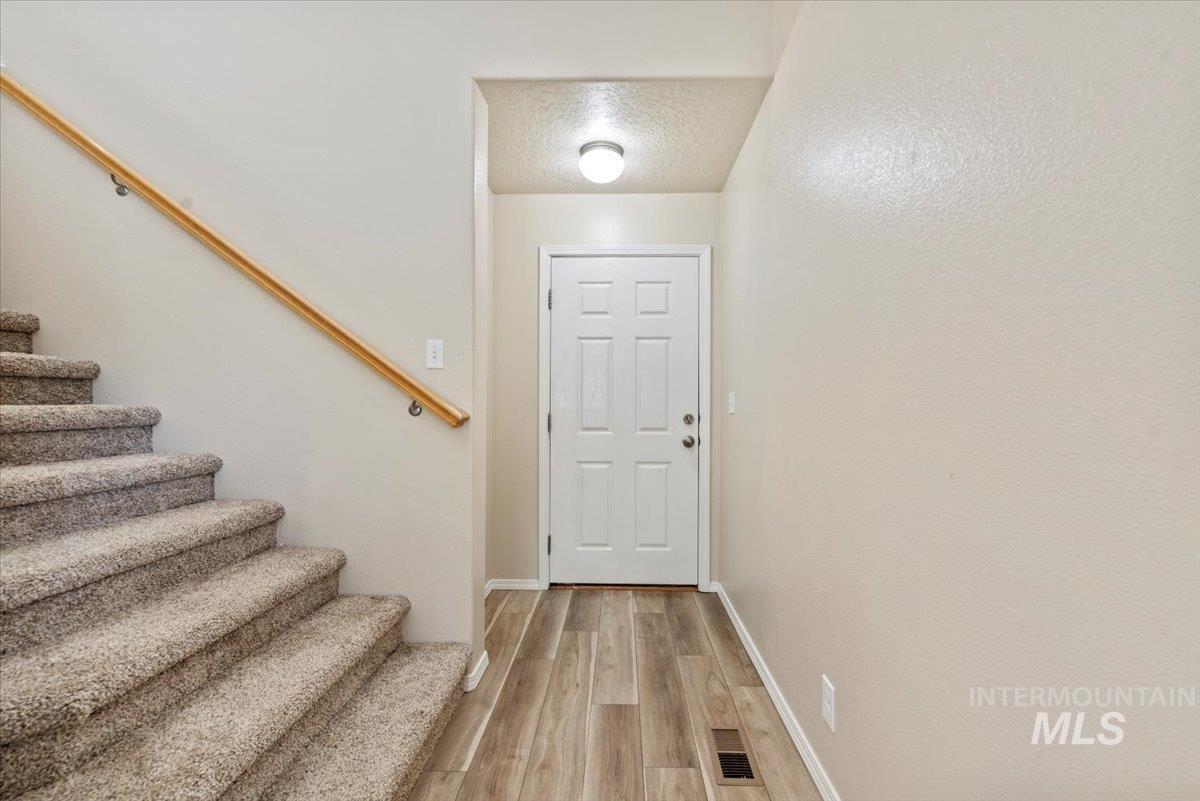 994 North Gray Cloud Way Meridian, ID 83642 - Photo 6 of 28 Entryway featuring wood finished floors, a textured ceiling, and stairs