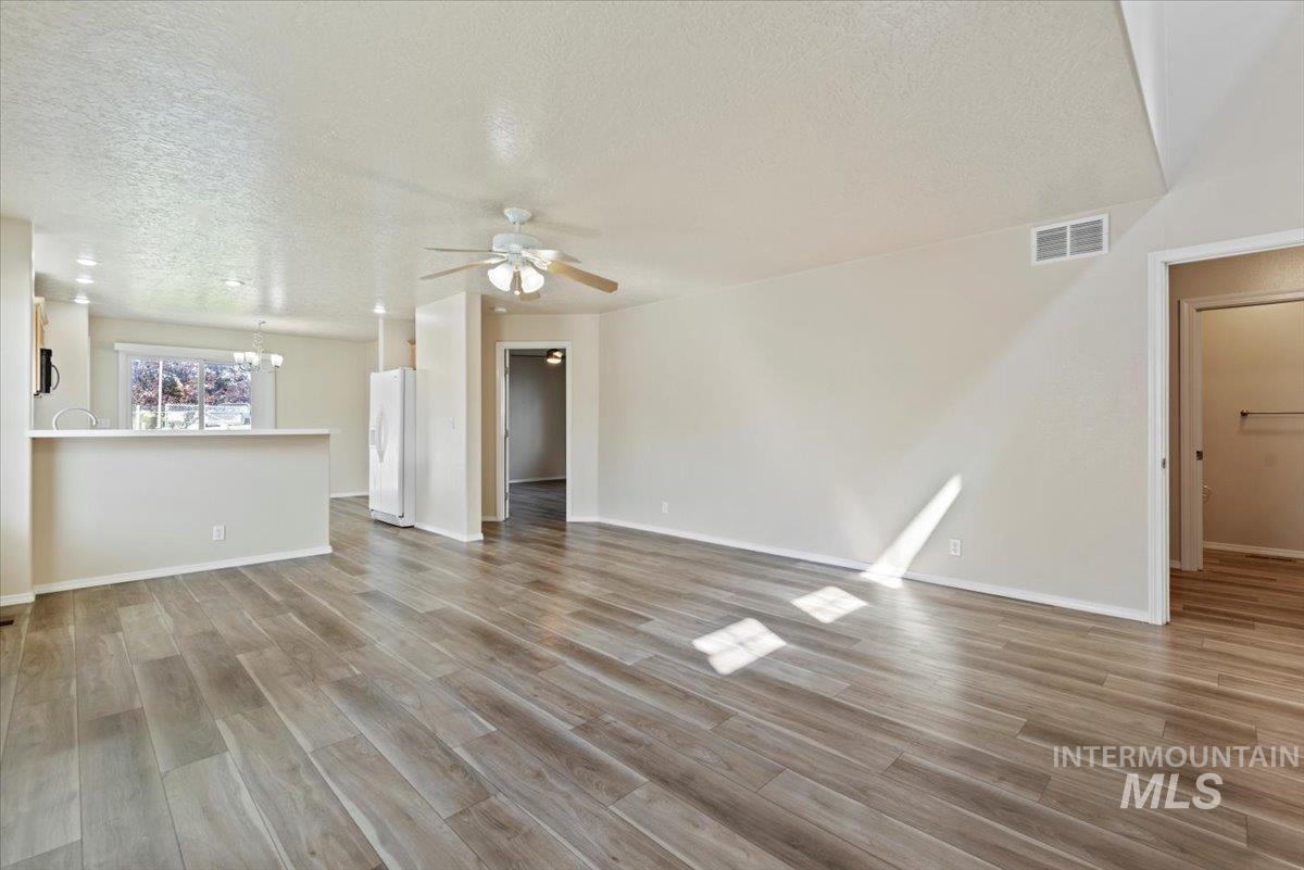 994 North Gray Cloud Way Meridian, ID 83642 - Photo 7 of 28 Unfurnished living room with a textured ceiling, light wood-type flooring, a ceiling fan, and a chandelier