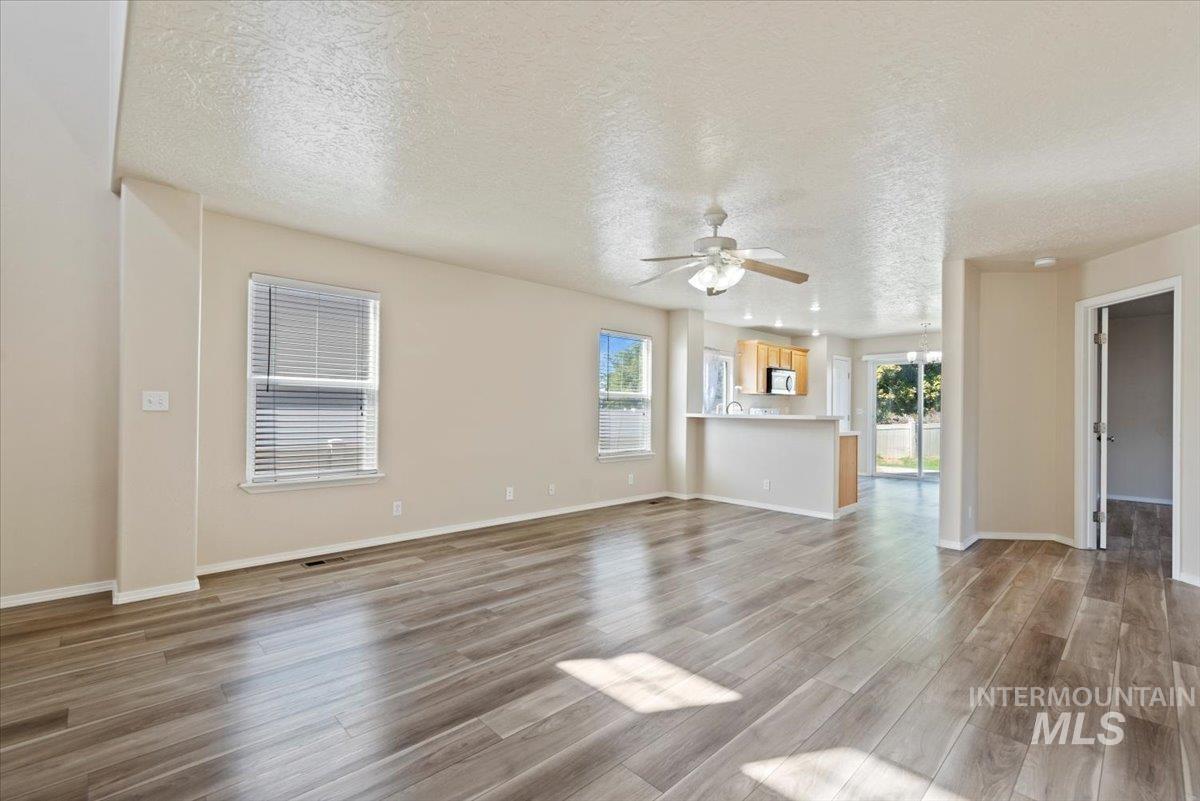 994 North Gray Cloud Way Meridian, ID 83642 - Photo 8 of 28 Unfurnished living room with a textured ceiling, plenty of natural light, light wood-type flooring, and ceiling fan