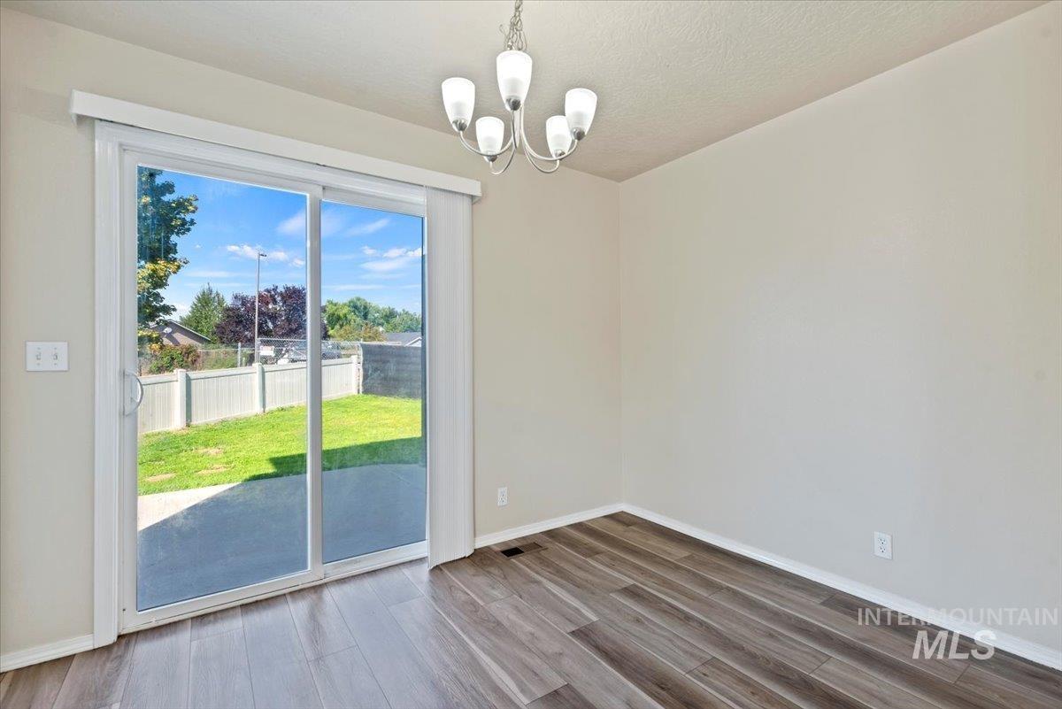 994 North Gray Cloud Way Meridian, ID 83642 - Photo 10 of 28 Unfurnished dining area featuring wood finished floors, a chandelier, and a textured ceiling