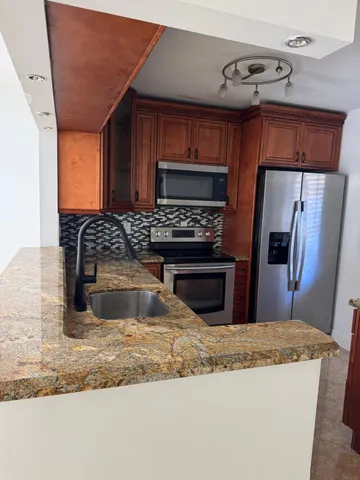 a kitchen with stainless steel appliances granite countertop a sink a stove and a refrigerator