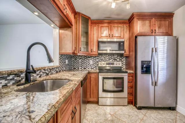 a kitchen with a sink cabinets stainless steel appliances and a window