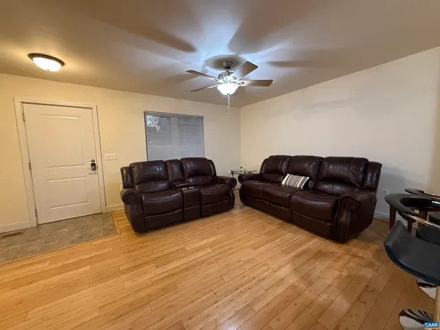 a living room with furniture a ceiling fan a lamp and a rug