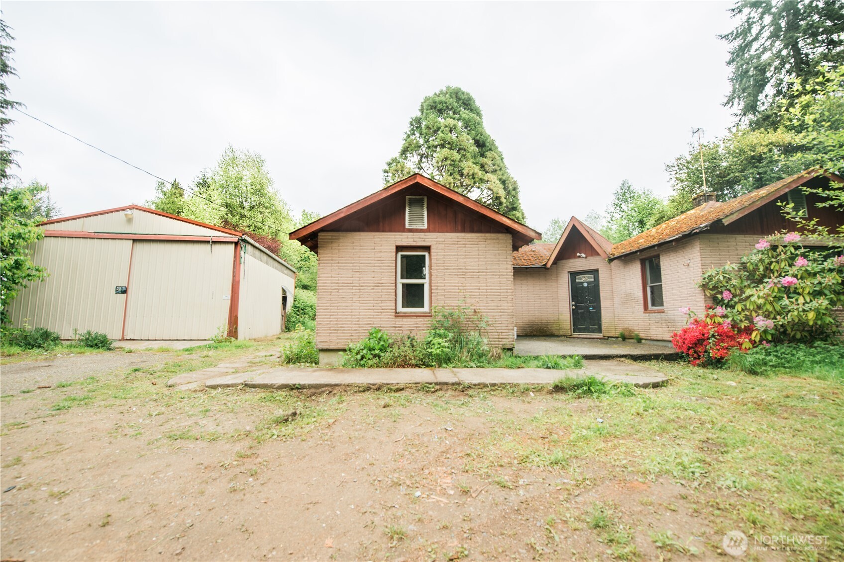 10379 Bethel Burley Road Southeast Port Orchard, WA 98367 - Photo 6 of 40 a white house with a small yard plants and large tree