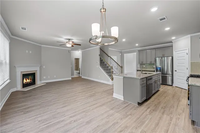 a kitchen with granite countertop a stove top oven a sink dishwasher a dining table and chairs with wooden floor