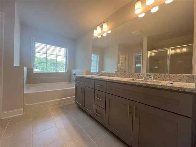 a bathroom with a granite countertop sink a large mirror and a bathtub