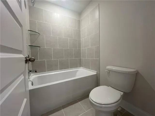 a white toilet sitting next to a bath tub and a shower