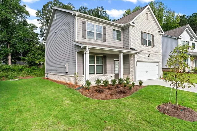 a view of a yard in front of a house with plants and large tree