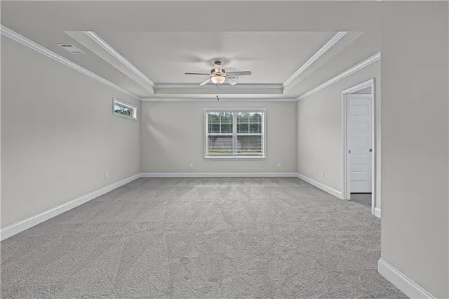 an empty room with a chandelier fan and windows