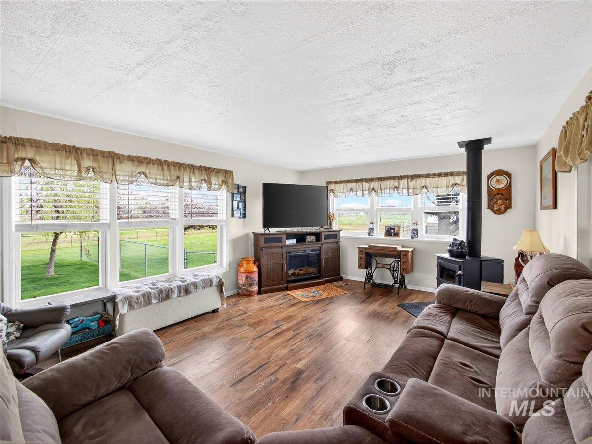 9228 Washoe Road Payette, ID 83661 - Photo 13 of 49 Living area featuring wood finished floors, a wood stove, and a textured ceiling