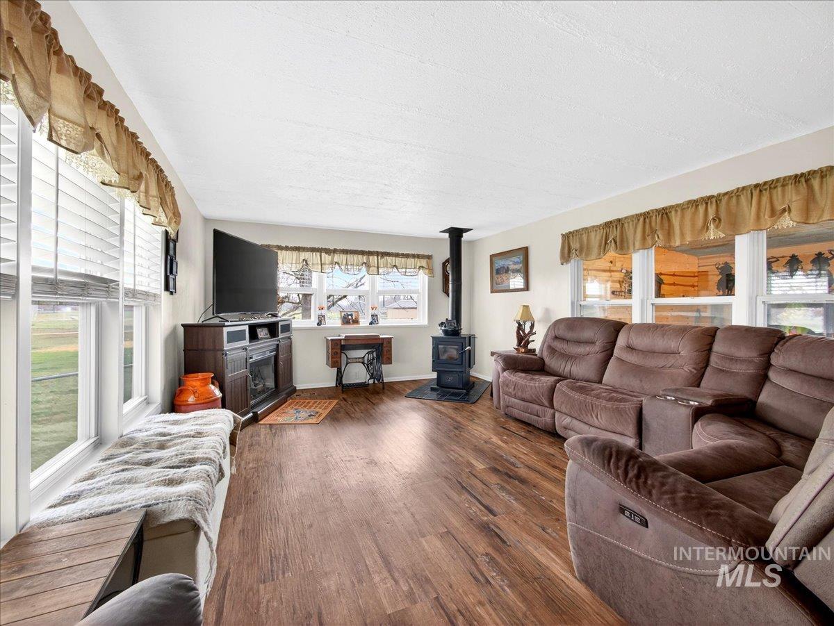 9228 Washoe Road Payette, ID 83661 - Photo 14 of 49 Living room featuring a wood stove, dark wood finished floors, healthy amount of natural light, and a textured ceiling