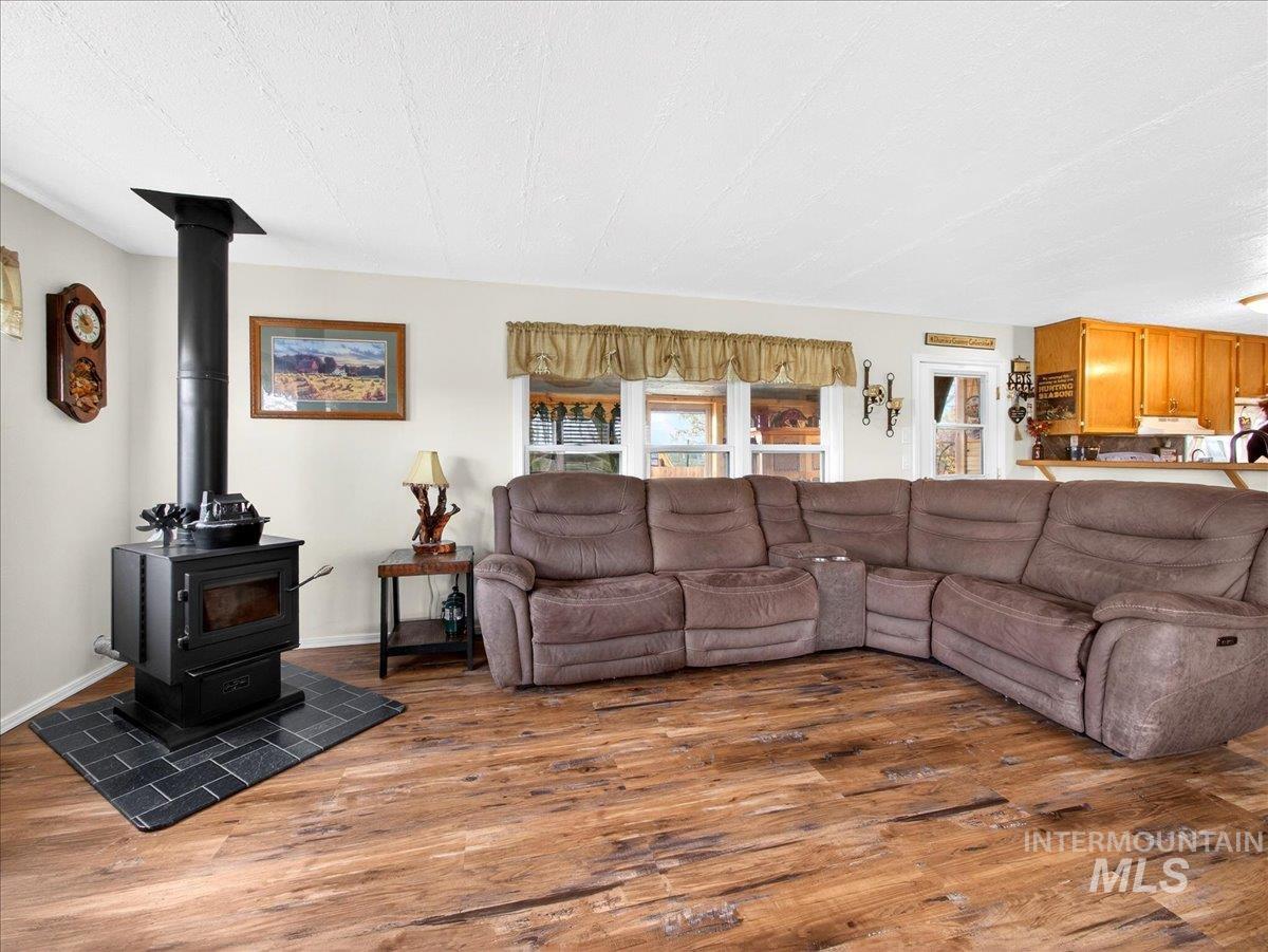 9228 Washoe Road Payette, ID 83661 - Photo 16 of 49 Living area featuring dark wood-style flooring, a wood stove, and a textured ceiling