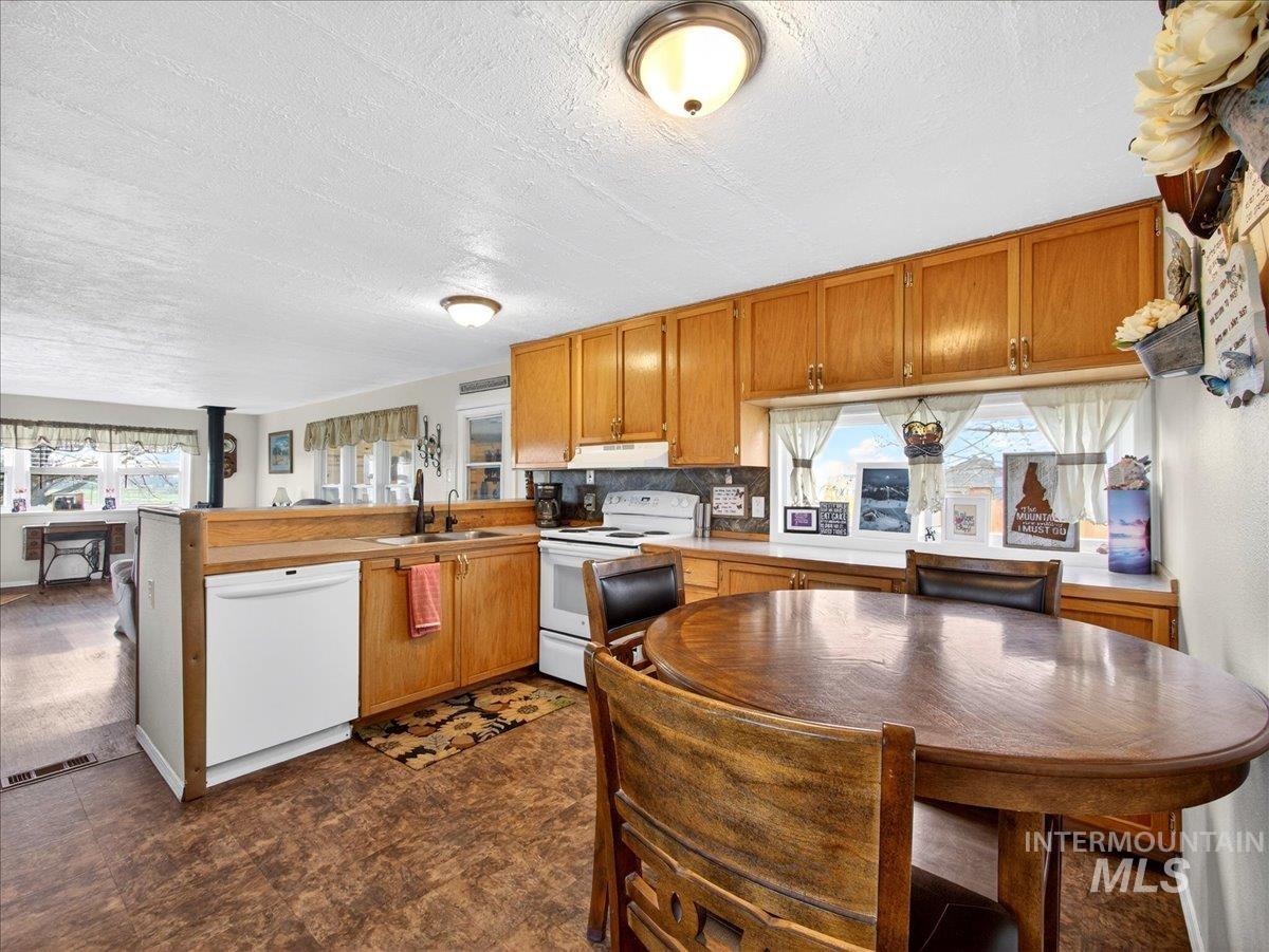 9228 Washoe Road Payette, ID 83661 - Photo 49 of 49 Kitchen featuring white appliances, a peninsula, wood finish cabinetry, open floor plan, and a textured ceiling
