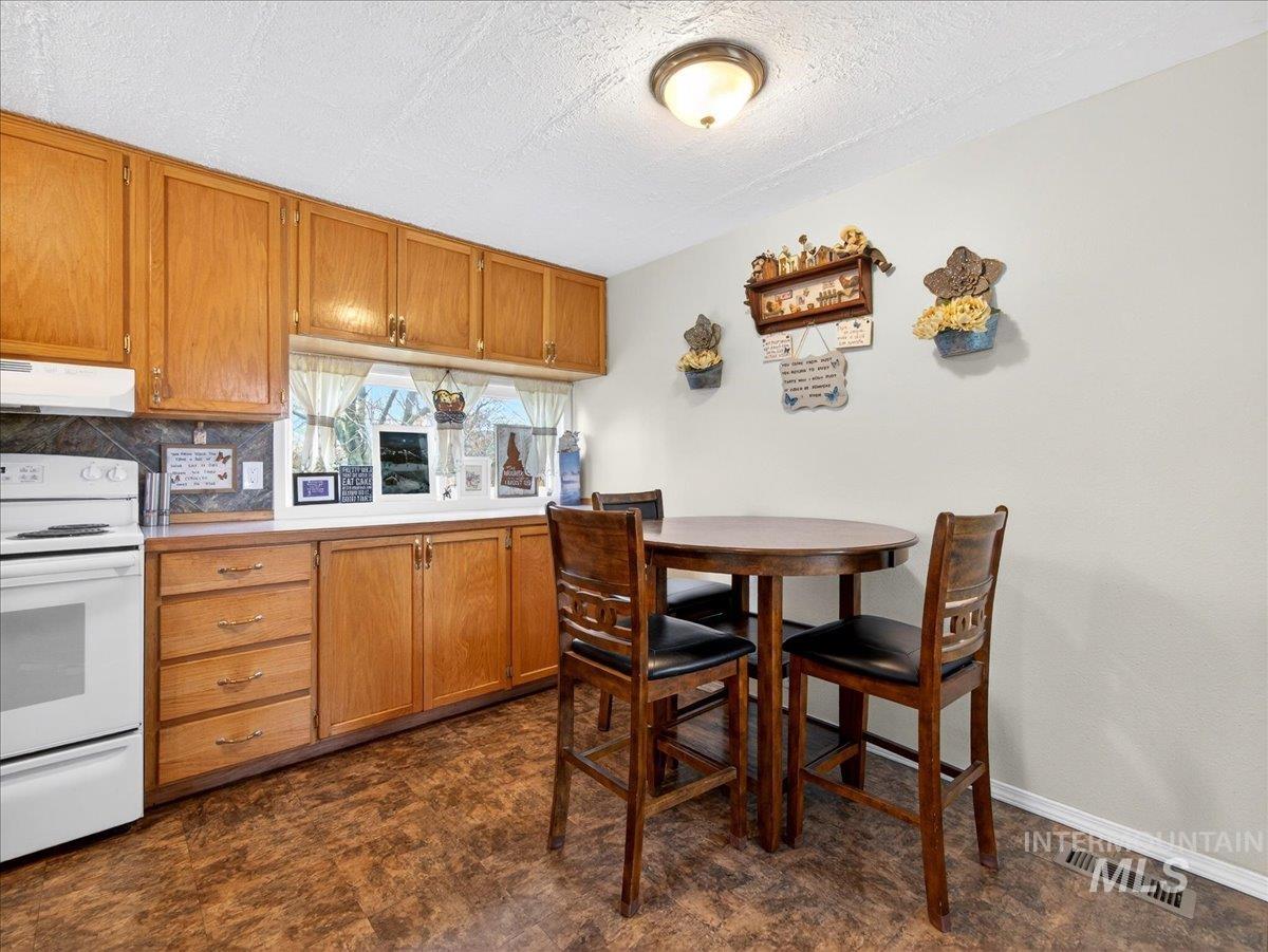 9228 Washoe Road Payette, ID 83661 - Photo 22 of 49 Kitchen with electric range, wood finish cabinets, a textured ceiling, light countertops, and tasteful backsplash