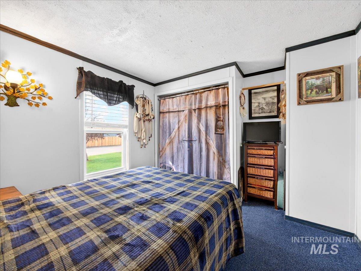 9228 Washoe Road Payette, ID 83661 - Photo 26 of 49 Bedroom with dark carpet, crown molding, a textured ceiling, and a closet