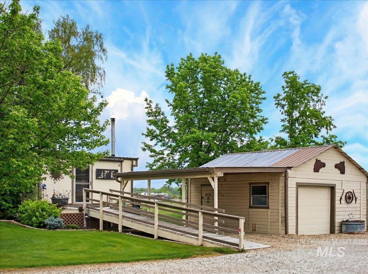 9228 Washoe Road Payette, ID 83661 - Photo 7 of 49 View of front of house featuring a wooden deck, a garage, a metal roof, and a front yard