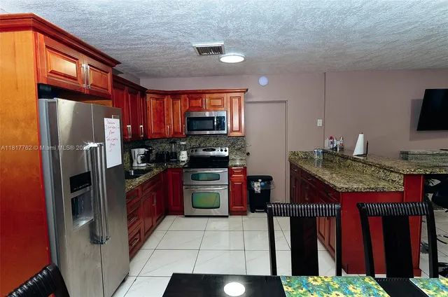 a kitchen with stainless steel appliances granite countertop a refrigerator a stove and a sink