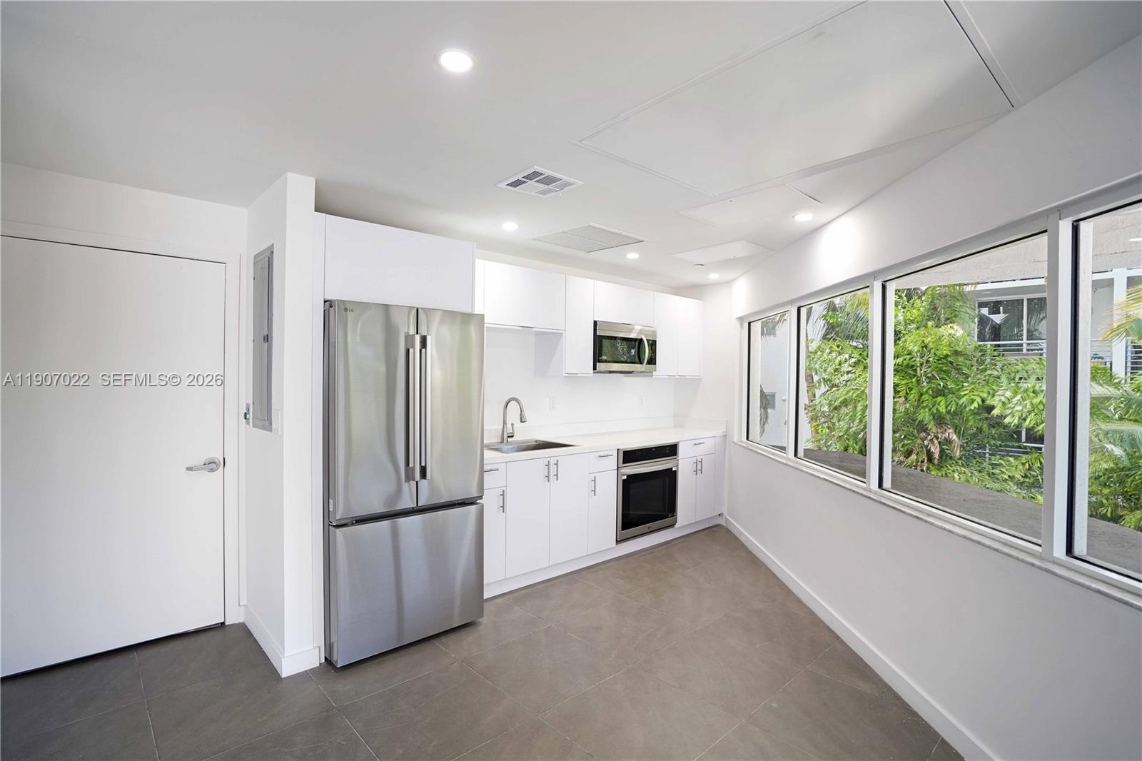 1621 Bay Road, Unit 604 Miami Beach, FL 33139 - Photo 21 of 30 a kitchen with granite countertop stainless steel appliances a refrigerator cabinets and wooden floor