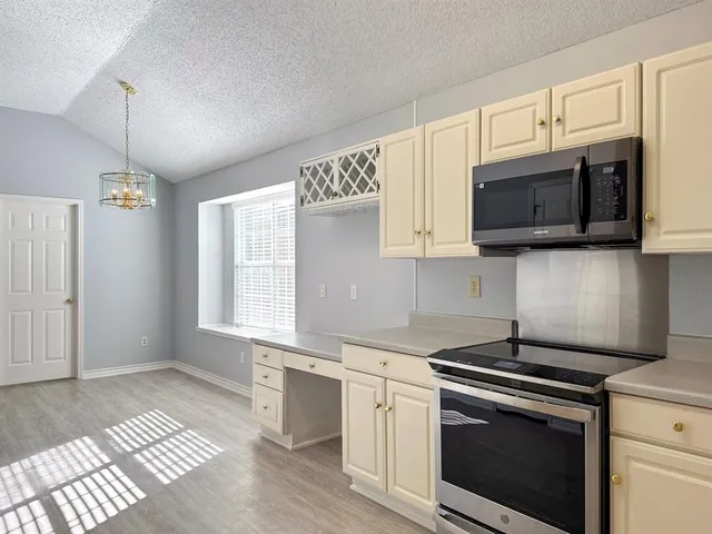 a kitchen with stainless steel appliances granite countertop a stove a microwave and a white cabinets