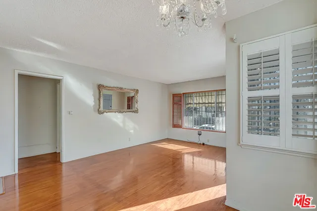 a view of an empty room with window and wooden floor