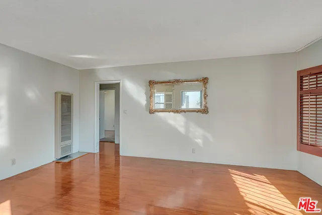 a view of a big room with wooden floor and windows