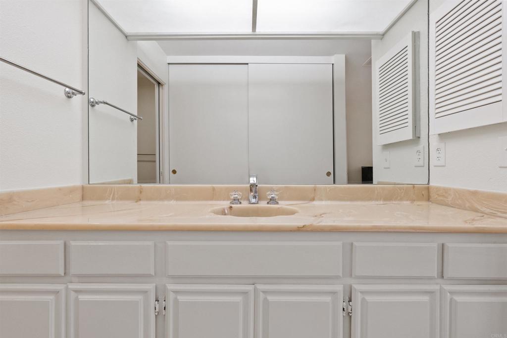 17607 Pomerado Road, Unit 101 San Diego, CA 92128 - Photo 24 of 39 a bathroom with a granite countertop sink and white cabinets
