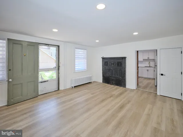 a view of an empty room with a window and a kitchen