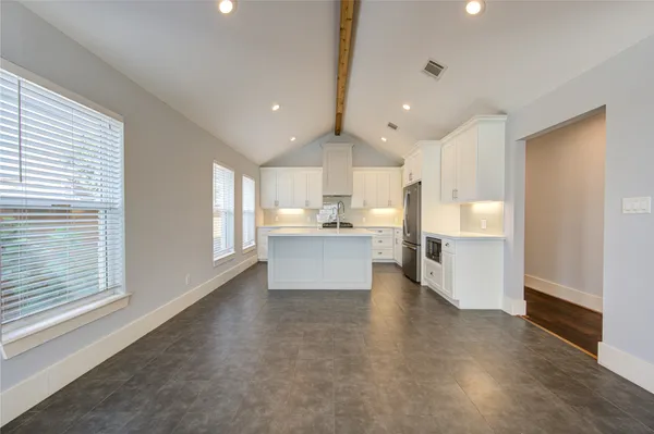 a view of kitchen with kitchen island white cabinets and stainless steel appliances