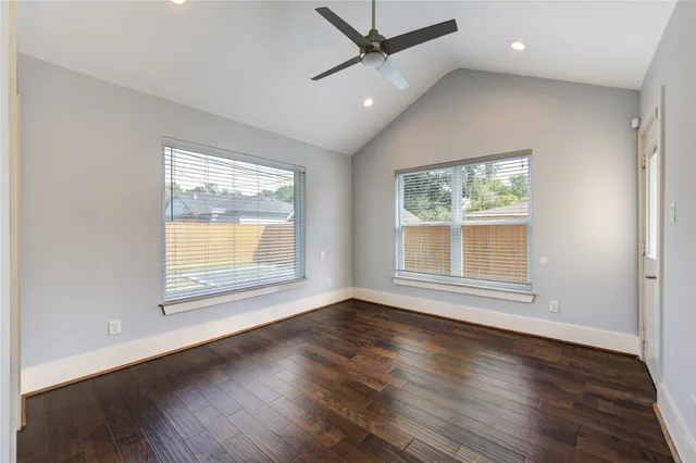 an empty room with wooden floor and windows
