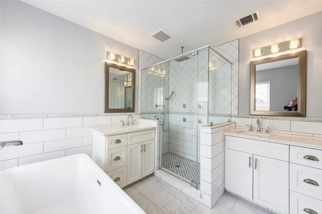 a bathroom with a double vanity sink mirror and bathtub
