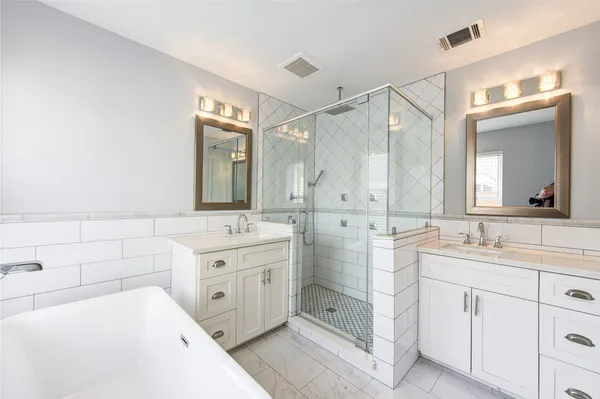a bathroom with a double vanity sink mirror and bathtub