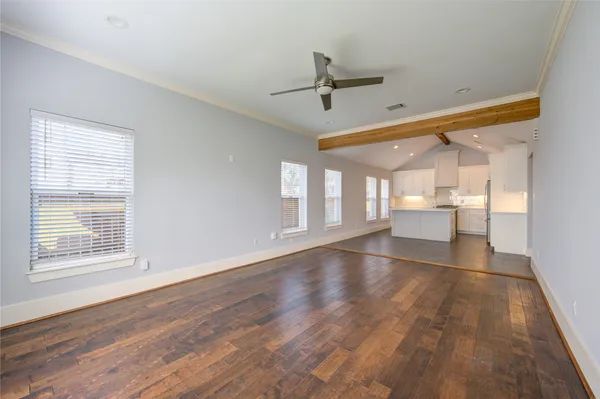 a view of an empty room with a window and wooden floor