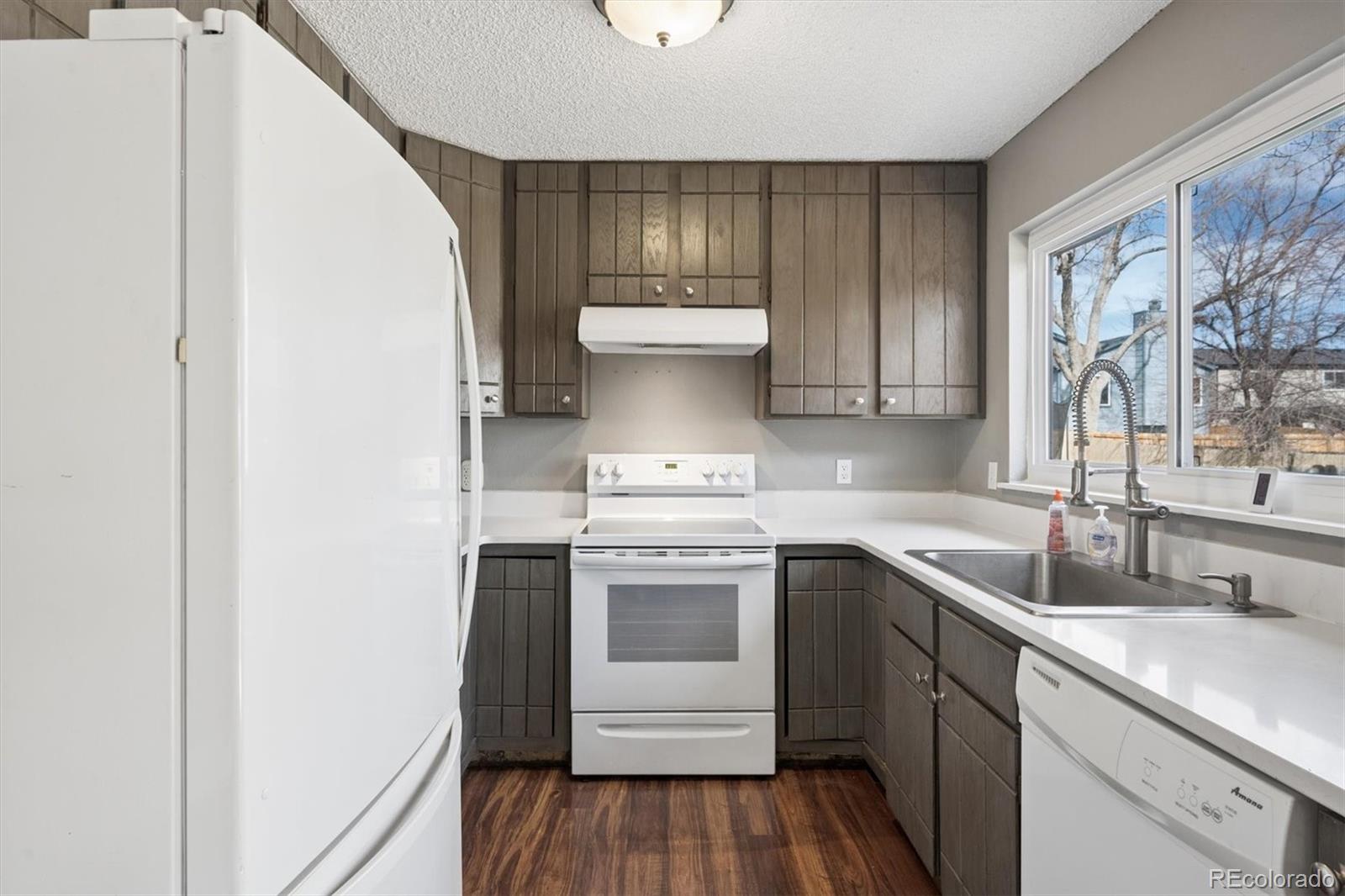 9802 Garrison Court Westminster, CO 80021 - Photo 11 of 34 a kitchen with a sink cabinets and wooden floor