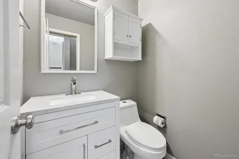 a bathroom with a granite countertop toilet sink and mirror