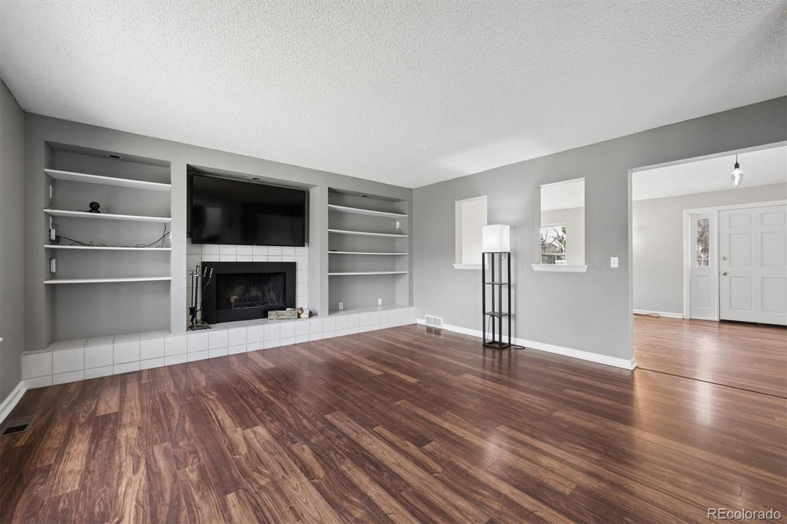 9802 Garrison Court Westminster, CO 80021 - Photo 6 of 34 a view of an empty room with wooden floor and a fireplace