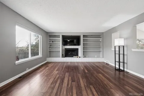 an empty room with wooden floor windows and a fireplace