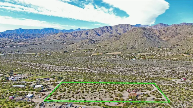 a view of a lush green field with mountains in the background