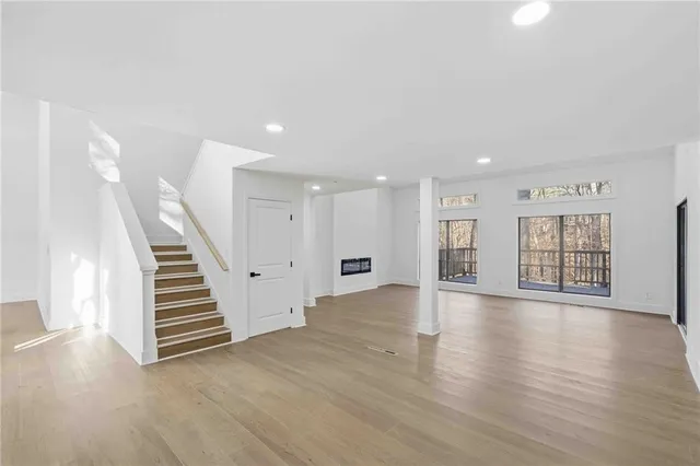 a view of an empty room with wooden floor and stairs
