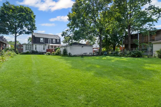 a view of a house with a big yard and large trees