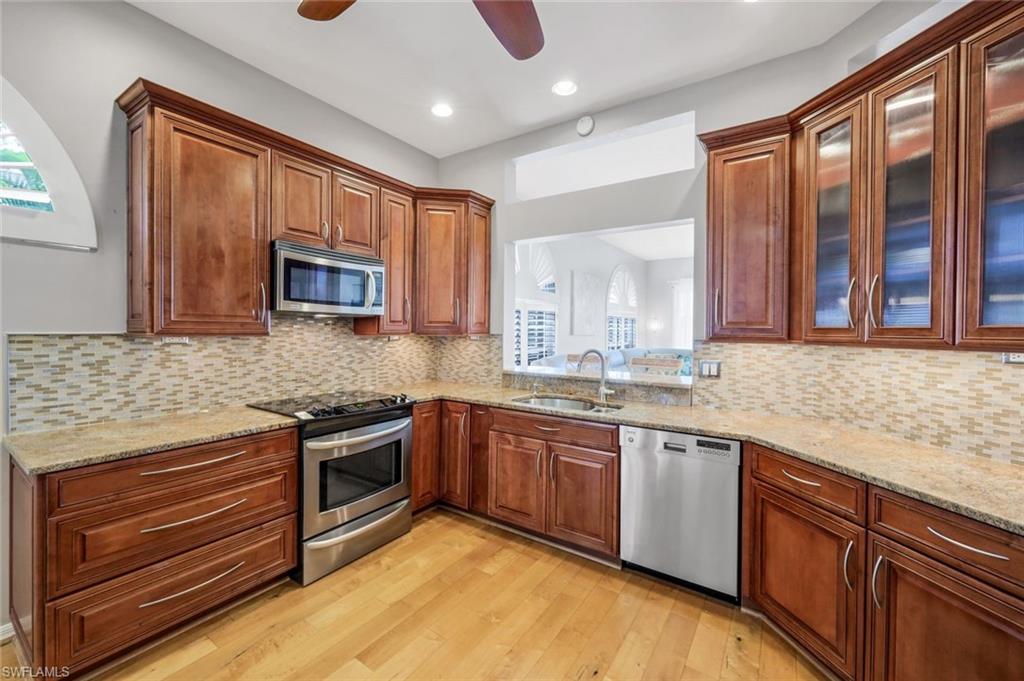 11384 Quail Village Way, Unit 203 Naples, FL 34119 - Photo 14 of 48 a kitchen with stainless steel appliances granite countertop wooden cabinets and a stove top oven