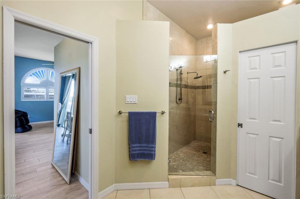 11384 Quail Village Way, Unit 203 Naples, FL 34119 - Photo 22 of 48 a bathroom with a glass shower door and a sink