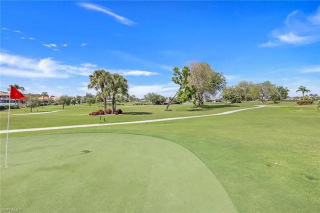 a view of a white house with a big yard plants and large trees