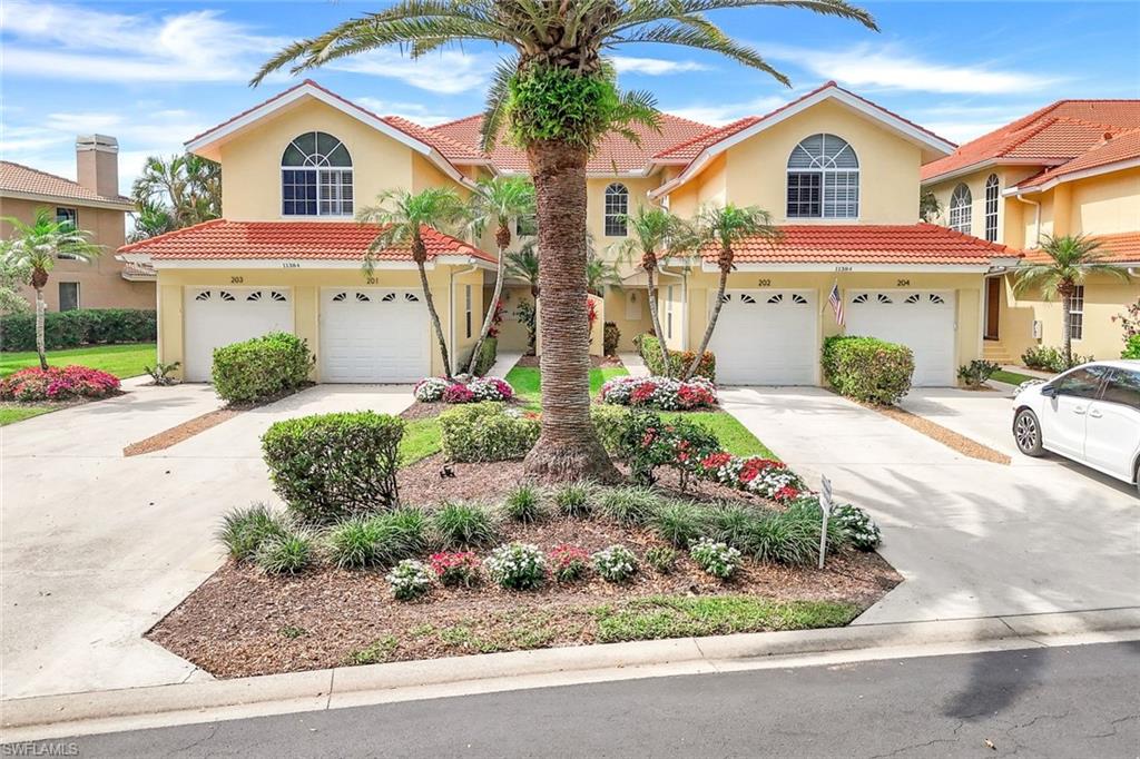 11384 Quail Village Way, Unit 203 Naples, FL 34119 - Photo 32 of 48 a view of a white house with large windows and outdoor space