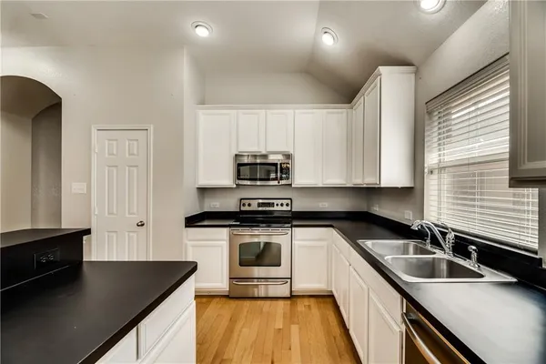 a kitchen with granite countertop a sink a stove and cabinets