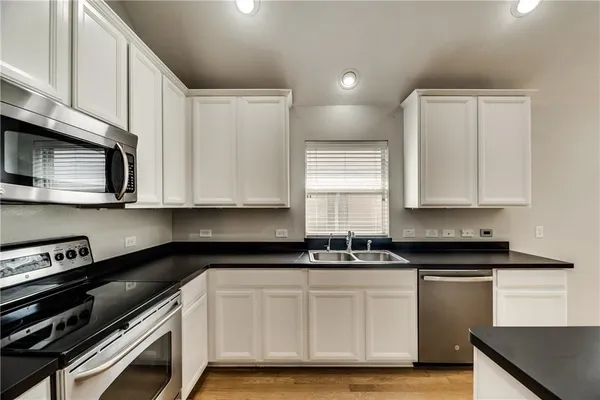 a kitchen with granite countertop white cabinets and black appliances
